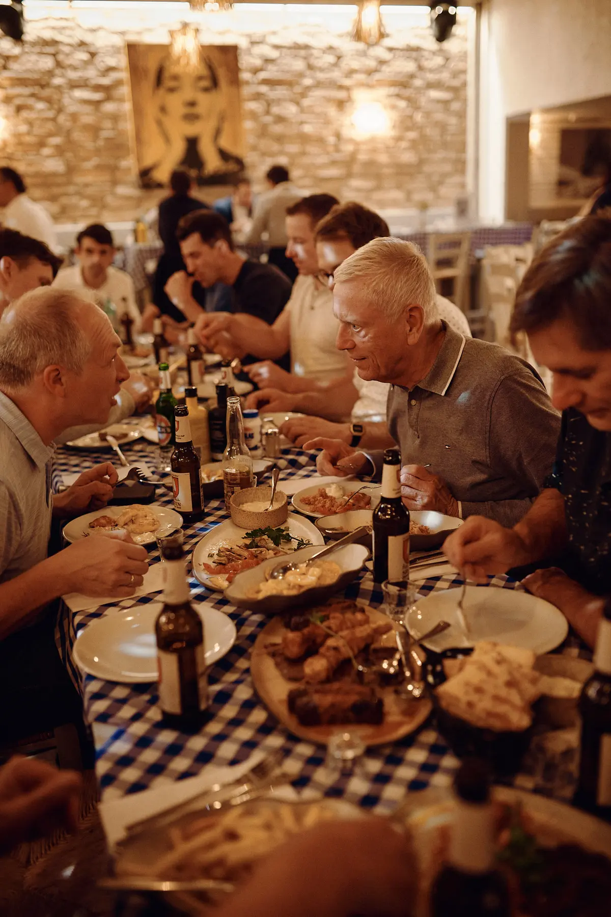 Lange gedeckte Tafel im griechischen Restaurant, die Teilnehmer essen und unterhalten sich